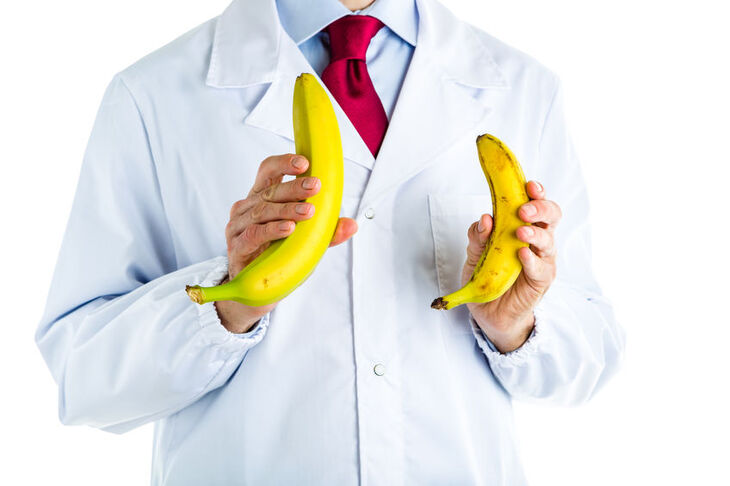 Lekarz w białym fartuchu trzymający w dłoniach dwa banany o różnej wielkości