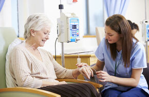 Pielęgniarka siedząca przy starszej kobiecie podczas chemioterapii 