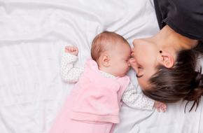 Kobieta całująca w czoło śpiące niemowlę