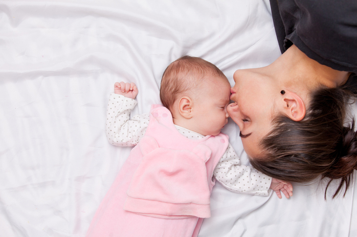 Kobieta całująca w czoło śpiące niemowlę