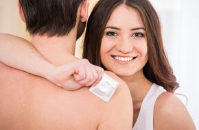 Uśmiechnięta kobieta z prezerwatywą w dłoni