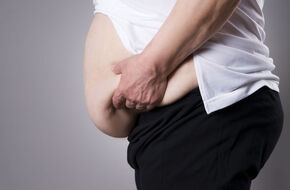 Patologicznie otyły mężczyzna trzymający się za brzuch