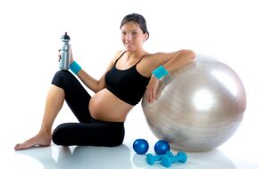 Kobieta w zaawansowanej ciąży siedząca przy piłce do ćwiczeń