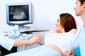 Kobieta w ciąży leżąca podczas badania ultrasonografem