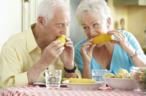 Starsza kobieta i mężczyzna jedzący kolby kukurydzy