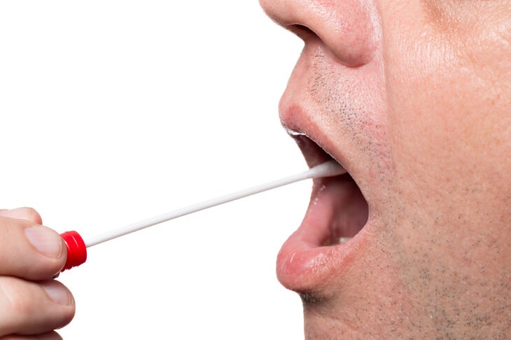 Mężczyzna pobierający próbkę wydzieliny z ust za pomocą specjalnego patyczka