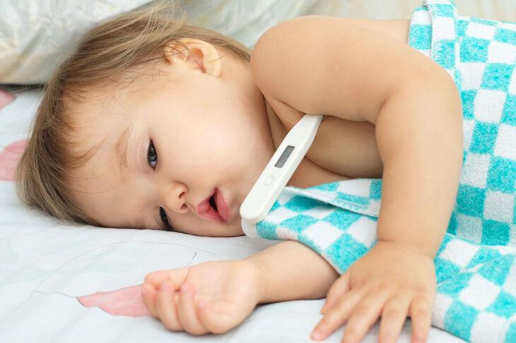 Osłabione dziecko z termometrem pod pachą