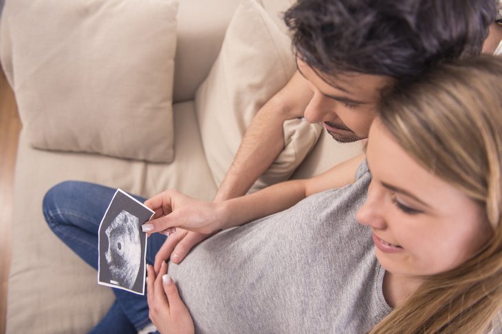 Kobieta w zaawansowanej ciąży patrząca na zdjęcie USG