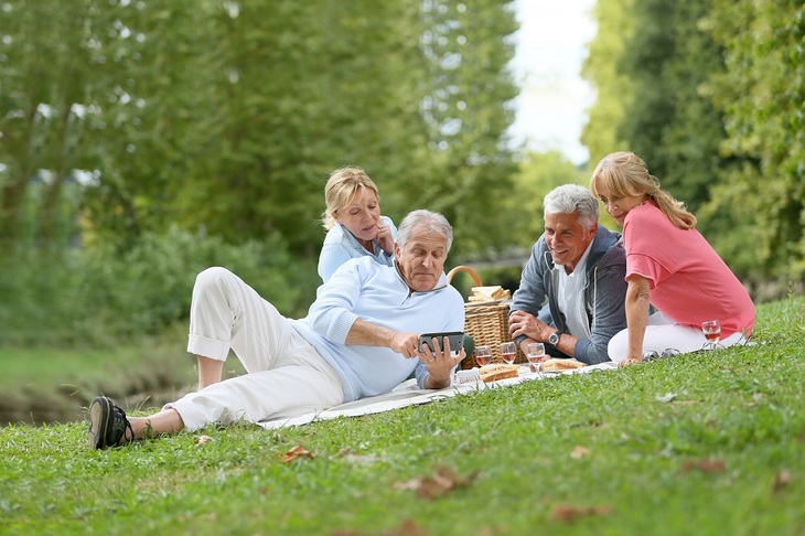 Seniorzy podczas pikniku siedzący na kocu