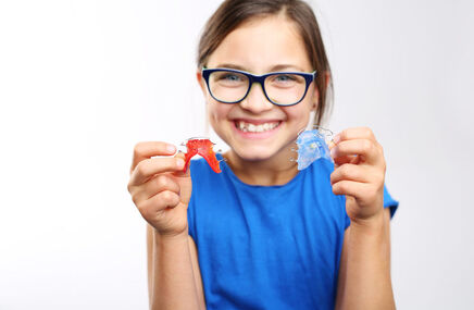 Dziewczynka pokazuje zdejmowany aparat ortodontyczny
